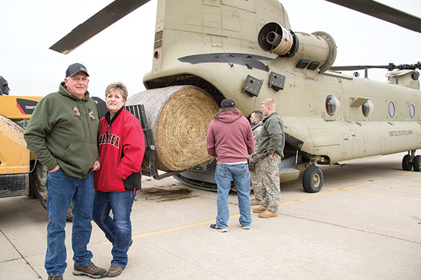 Jay and Kim schilling watch as the National Guard load hay bales for an airdrop
