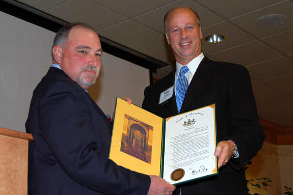 Pennsylvania Senator Mike Brubaker presents a senate proclamation recognizing the PFGC to President Scott Harkcom.