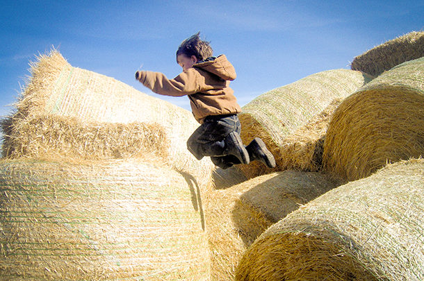 boy playing on hay bales